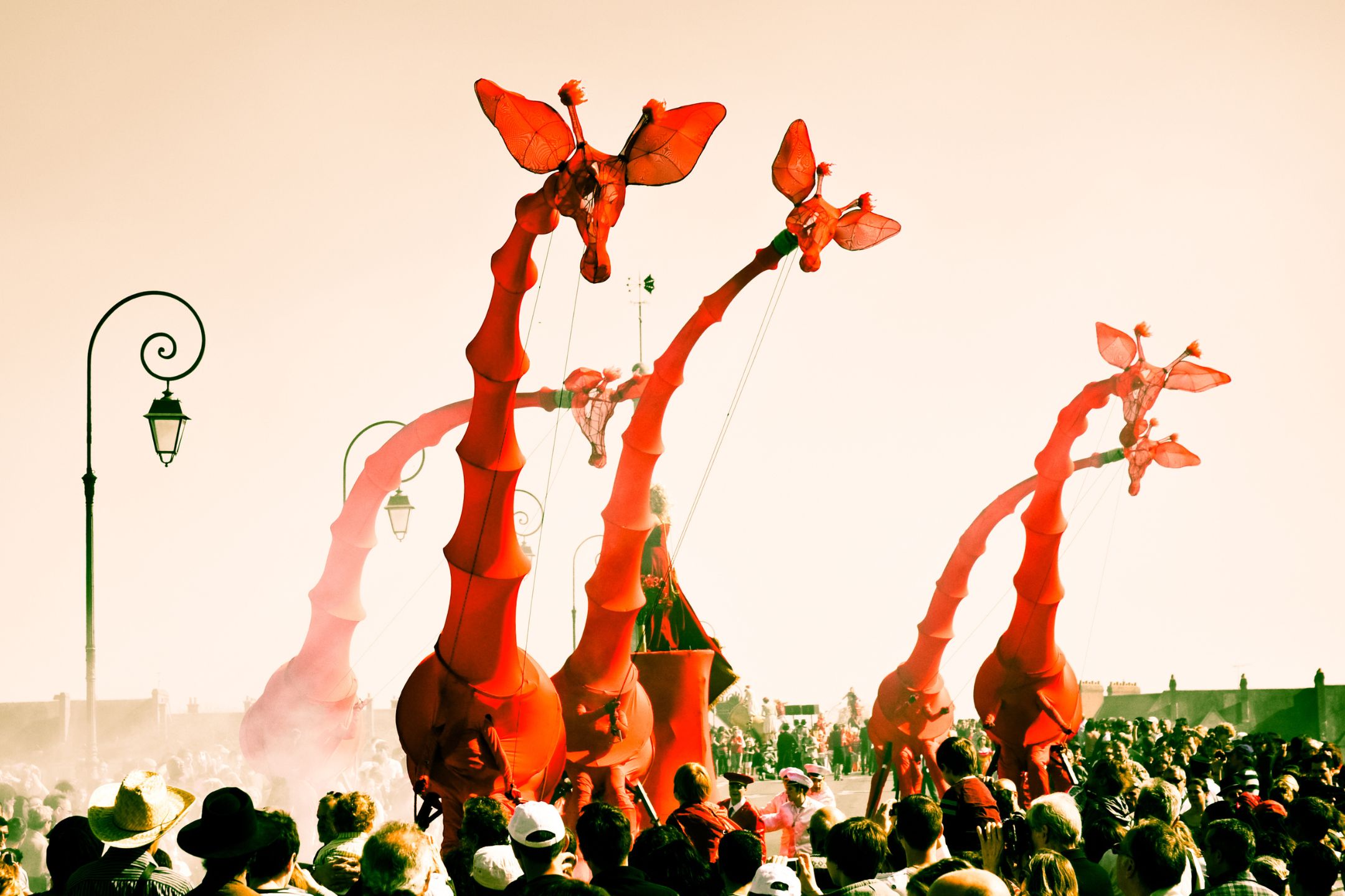 Street performers wear extraordinary red costumes, with long girafe-like necks
