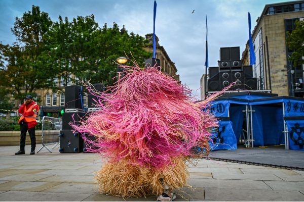 A street performer wears a fantastical pink outfit.