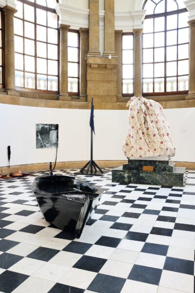 A photograph of the interior of Cartwright Hall gallery, showing several artworks, including a black boat and a statue covered in chintz fabric.