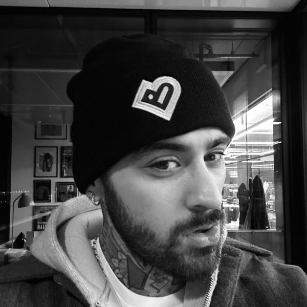 Black and white photo of Zayn Malik wearing a Bradford 2025 branded hat.