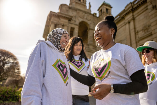 A group of volunteers stand in front of Cartwright Hall the two women in the front of the picture are laughing