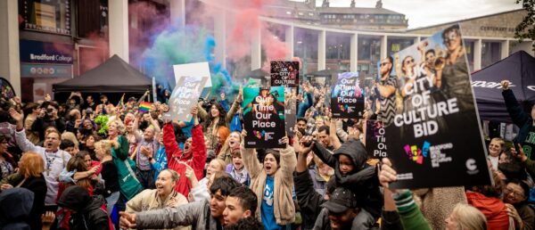 The people of Bradford celebrate the announcement that the city was awarded UK City of Culture 2025. A crowd of happy faces are gathered in Bradford City Centre holding placards that read: Our Time, Our Place.