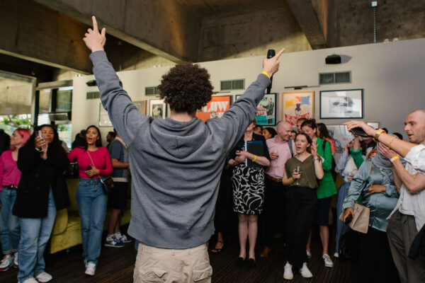 Musician in a grey hoodie performing in front of a crowd of people