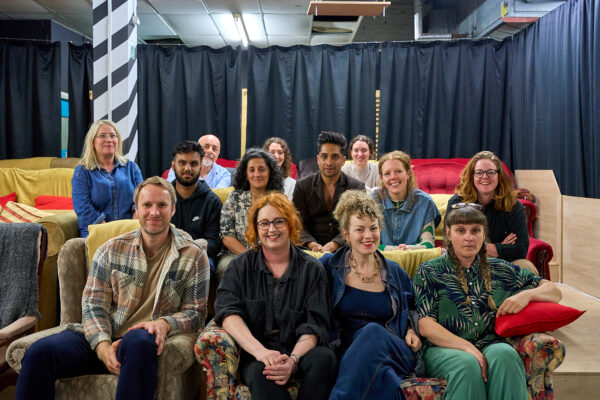 A group of people sit in rows, smiling towards the camera.