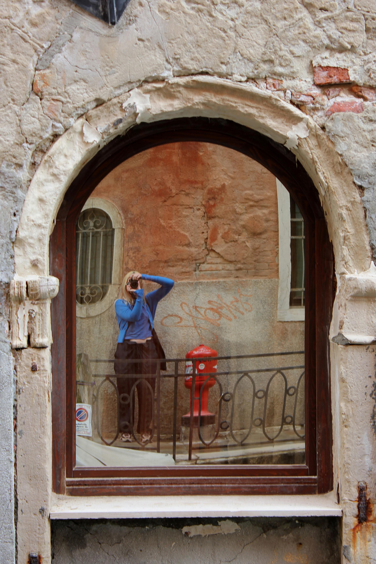 Artist Millie Sanders takes a selfie in a reflection in Venice.