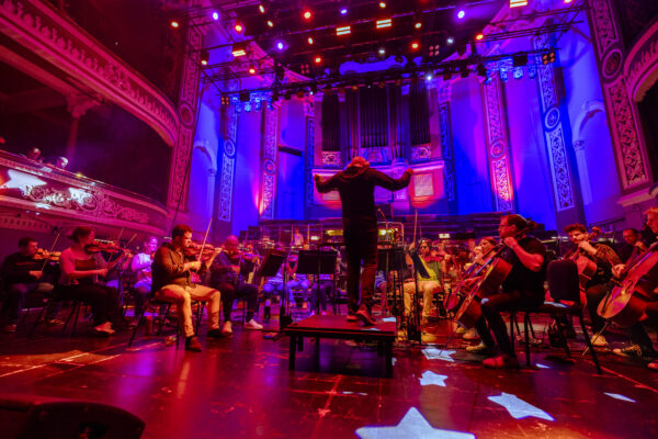 The orchestra play - lit in blue and red lights