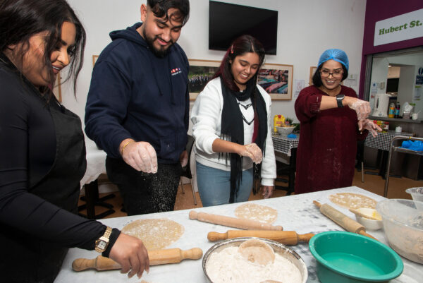 A group of people stand around a table preparing food.