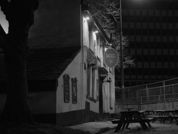 A black and white image of a pub on a dimly lit street.