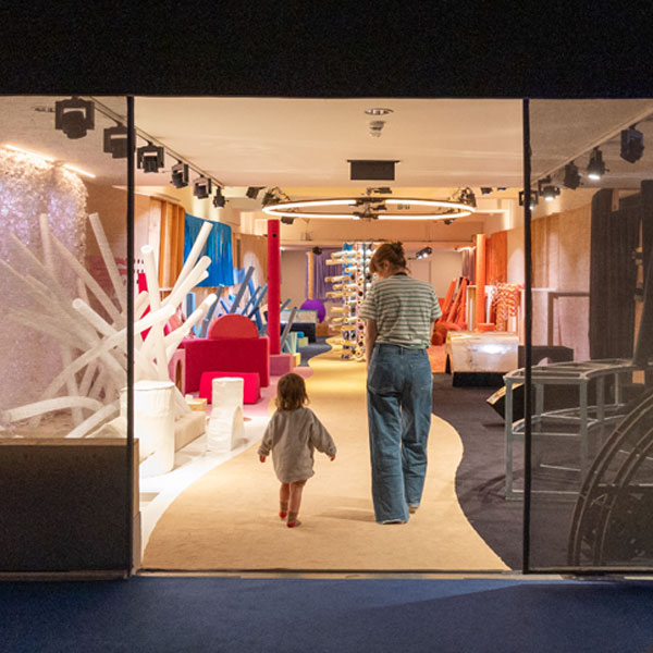 A mum and toddler walk through two glass doors into a soft play area