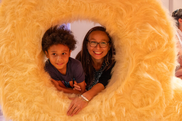 two young children peer through a circular hole in a fur lined wall