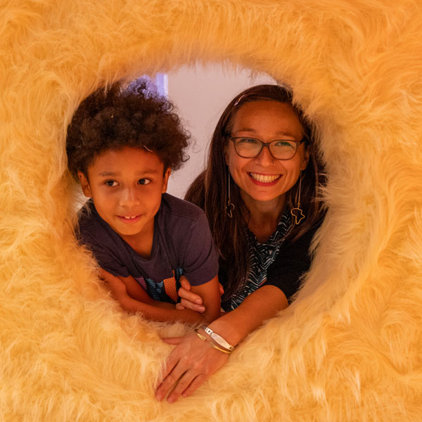 two young children peer through a circular hole in a fur lined wall