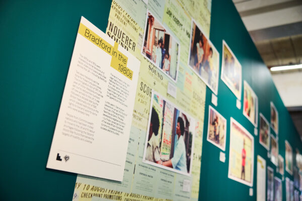 A blue wall of exhibition interpretation with photos.