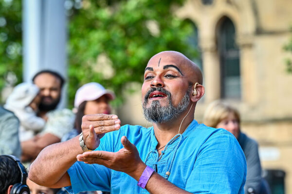 An outdoor performer mimes drinking tea.