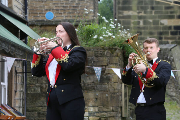 Two musicians from the Black Dyke Band stood on a yorkshire street playing brass instruments