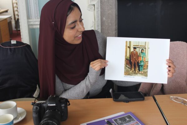 Young woman holding a photograph from the Apna Heritage Archive.