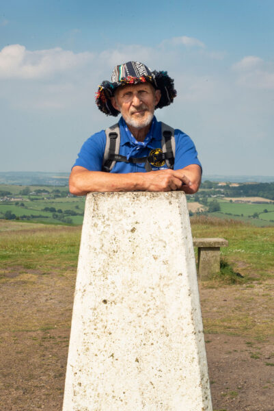 A walker standing at a white trig point.