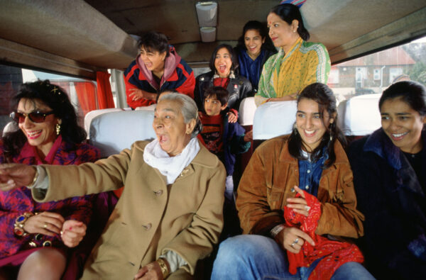 A group of people on a coach, smiling and laughing. A still from the film Bhaji on the Beach.