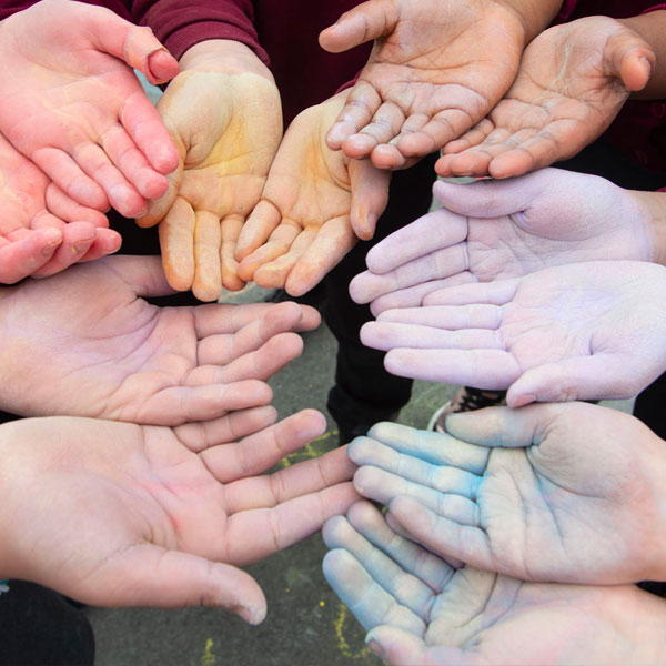 12 children's hands facing palm up painted in various colours.