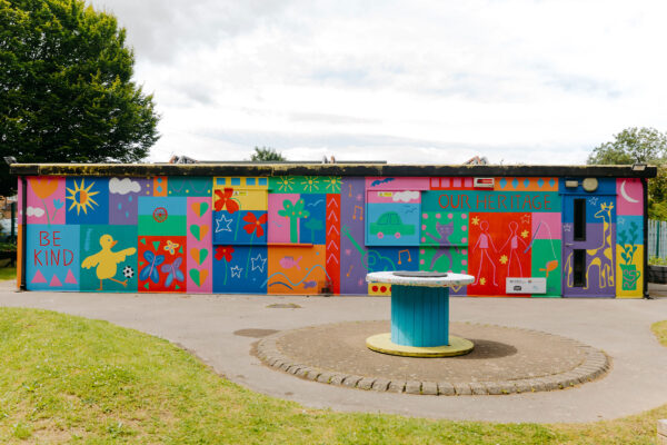 A colour ful mural on the side of a building in a park