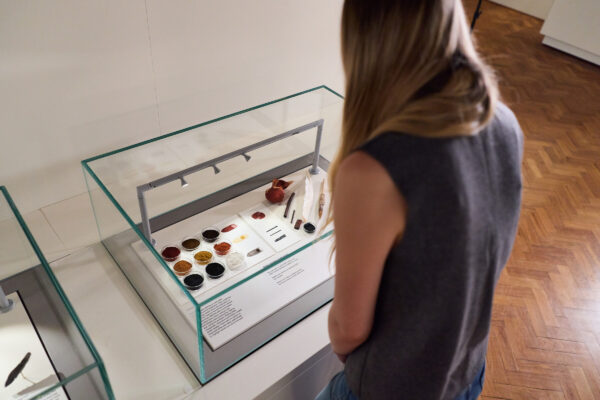 A woman looks into a case of objects.