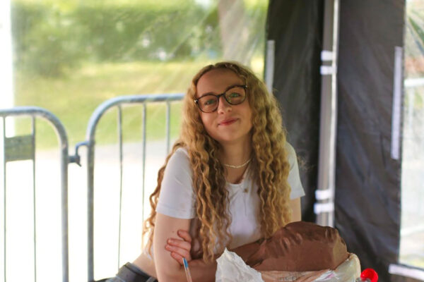 Artist Jessica Swift sits at a table with clay in front of her.