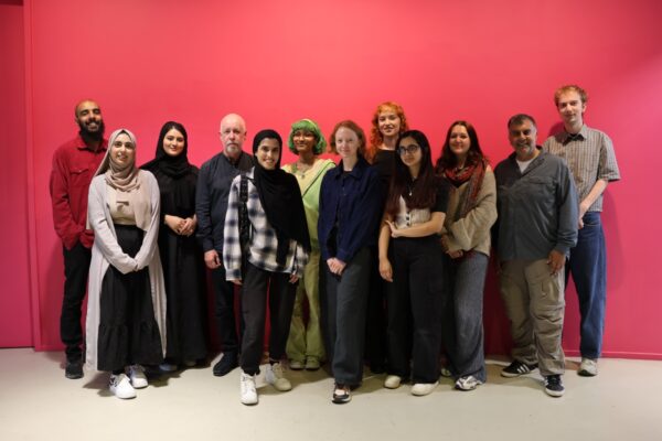 10 individuals standing infront of a red wall. These are the cohort who will be Bradford's Young Curators.