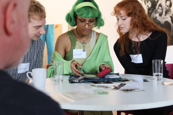 Three individuals sat at the end of a table looking at photographs.