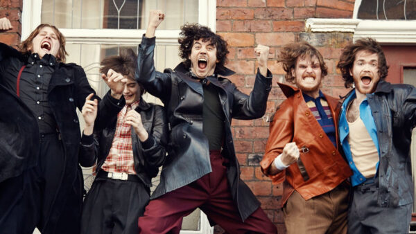 A group of people raise their fists in the air in celebration. A still from the film Northern Soul.