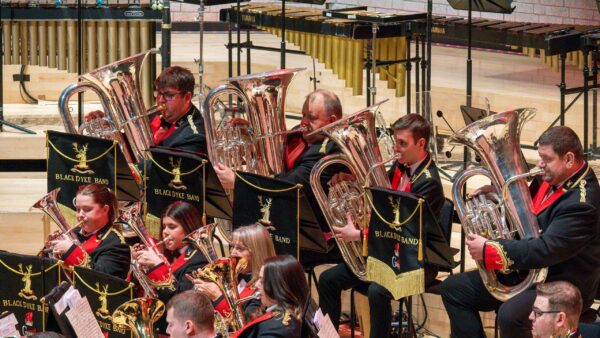 Smartly dressed people play brass instruments