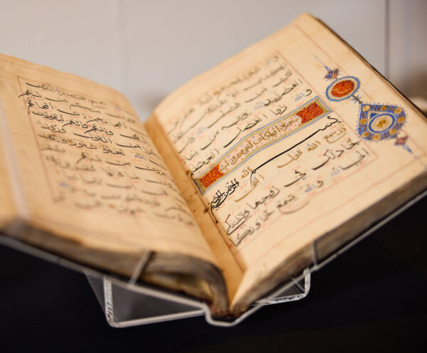 Close up picture of an open book including Arabic writing with decorative red and blue elements.