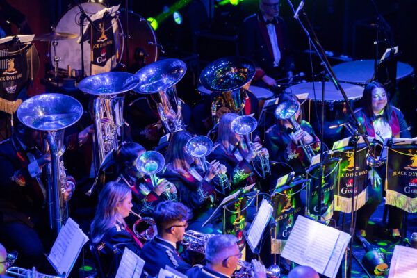 The brass section of a symphony orchestra perform on stage.