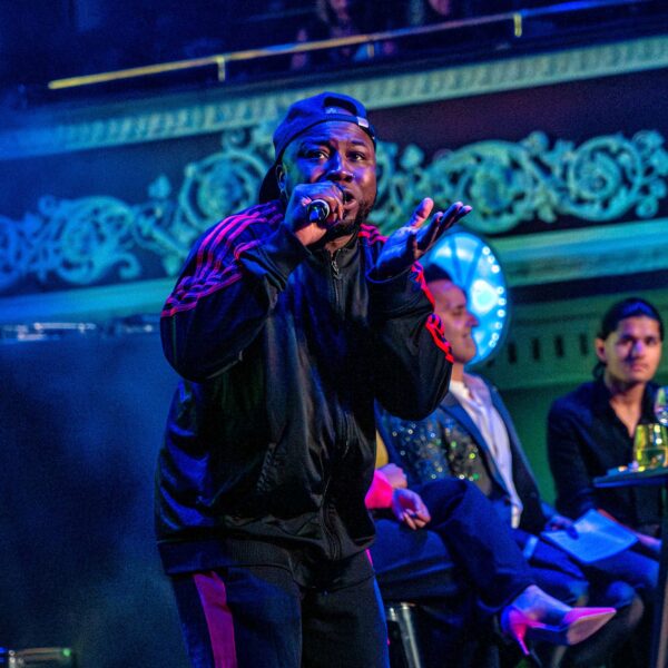 A young person wearing a cap and track suit performs on stage during a Bradford 2025 launch event.