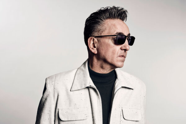 Portrait of Richard Hawley wearing sunglasses and a white jacket.