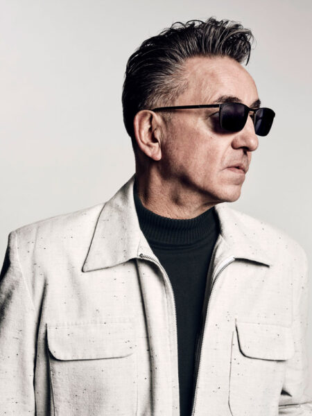 Portrait of Richard Hawley wearing sunglasses and a white jacket.