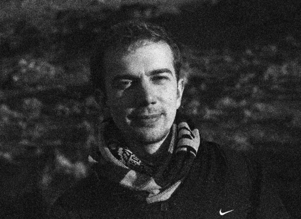 A grainy, black-and-white portrait of Louie Haslam-Chance. Louie is wearing a striped, knitted scarf tucked into a Nike jacket.