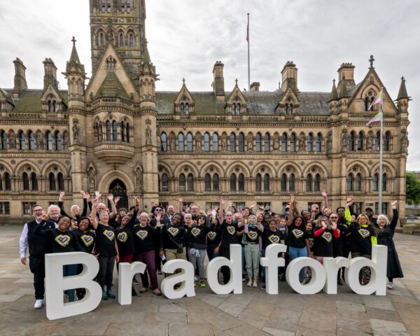 People throwing their hands in the air. Bradford City Hall in the background.