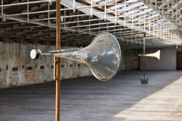 A metal horn on a pole in the roof space of a mill.