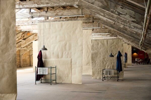 Giant hanging sheets of felt with cloaks on stands in front of them.
