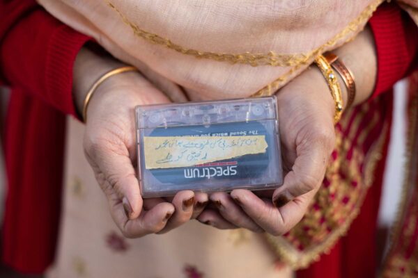 A man holds a plastic cassette tape.