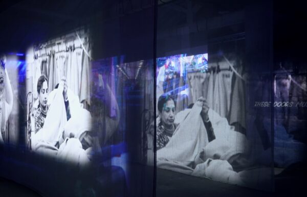 A projection of archive footage is projected onto fabric, suspended from the roof. It shows a woman handling a large amount of cloth