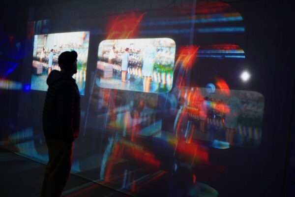 A figure looks at the projections - colourful blurs light up the image.