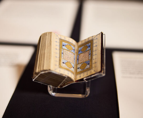 Close up image of small open book, with decorative gold and blue images on the page