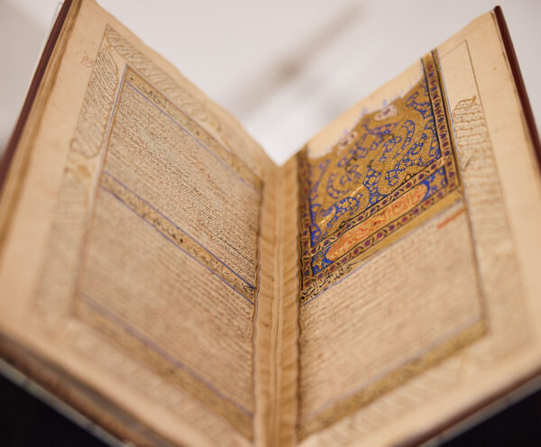 Open book with Arabic script and decorative golden elements.