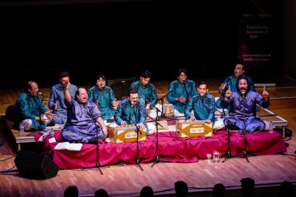 A group of performers sit on a stage playing traditional instruments.