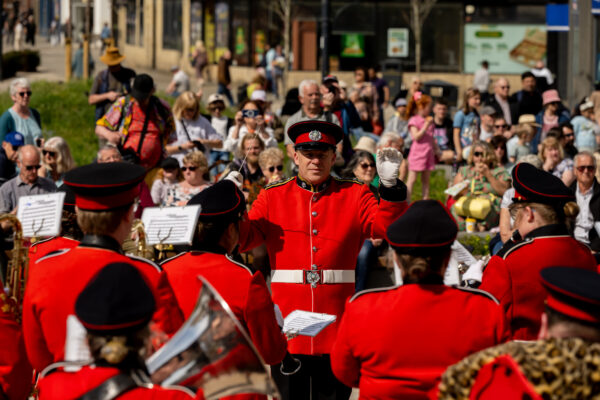 A man conducts a traditional brass band - they are all wearing traditional red uniforms.