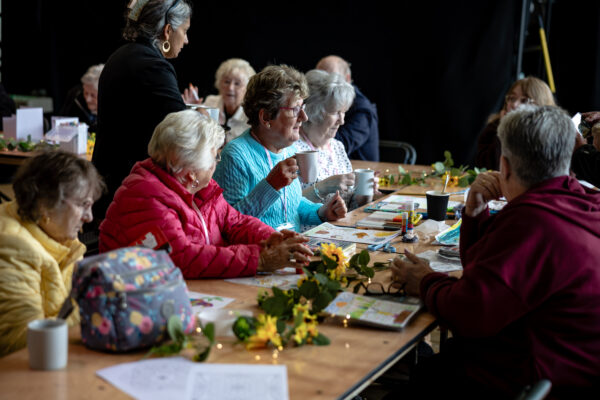 Lots of elderly ladies sat in a workshop together drawing