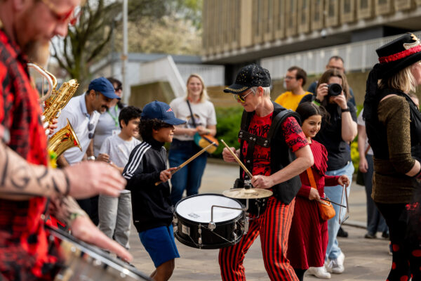 A man dums on a snare with a young boy.