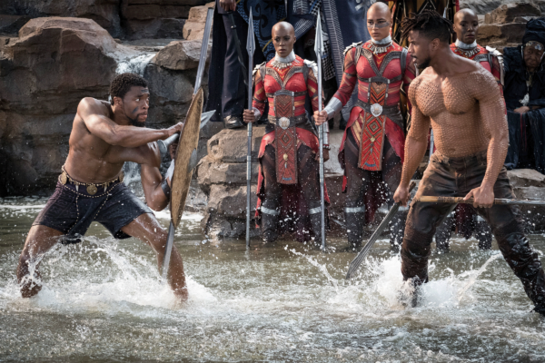 Two muscley men topless fighting with shields and spears in ankle deep water