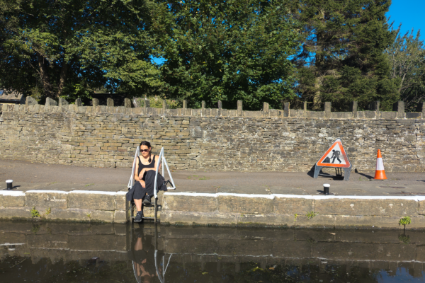Lady sat on the side of the canal, resting her feet on the steps
