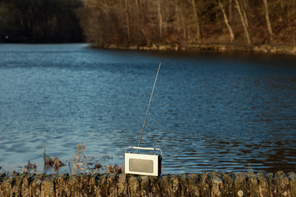 A radio rested on a wall, next to a body of water